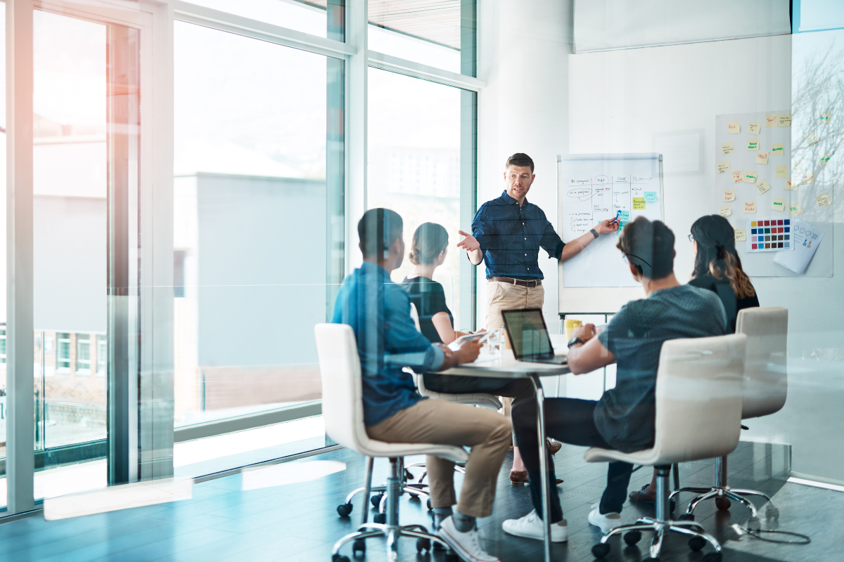 group of colleagues having a planning meeting with a leader at a whiteboard 